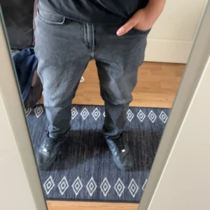 Svarta tapered jeans  - Säljer ett par svarta jeans från Jack & Jones med tapered passform. Jeansen har klassisk femficksdesign, normal midja och är tillverkade i mjukt denimtyg. Perfekta för dig som gillar en avslappnad men ändå stilren look.