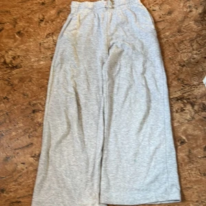 Grå mjukisbyxor med snörning - Ljusgrå mjukisbyxor med bred resår och snörning i midjan. Byxorna har en loose passform och raka ben, perfekta för chill dagar. Tillverkade i mjukt bomullsmaterial för extra komfort.