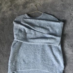 Ljusblå stickad tröja i alpackaull - Supermjuk ljusblå stickad tröja med rund hals och långa ärmar. Tröjan är tillverkad i en blandning av alpacka, ull, polyester och elastan vilket gör den både varm och skön. 