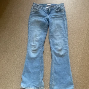 Blå bootcut jeans från Gina Tricot - Snygga ljusblå jeans från Gina Tricot i klassisk bootcut-modell. Jeansen har fem fickor, normal passform och är tillverkade i mjukt denimtyg. Perfekta för dig som gillar en retroinspirerad look med utsvängda ben.