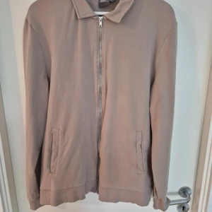Beige overshirt med dragkedja - Säljer en stilren beige overshirt från Dressmann i bomull. Jackan har dragkedja framtill, två fickor och klassisk krage. Perfekt för lager-på-lager och enkel att matcha med olika outfits.