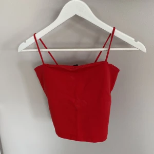 Röd croppad linnetopp Gina Tricot - Snygg röd croppad linnetopp från Gina Tricot med tunna axelband. Toppen är tillverkad i mjuk bomull och har en enkel, stilren design som passar perfekt till jeans eller kjol.