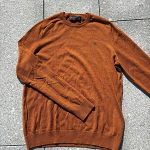 Rostbrun ulltröja från Morris XL - Säljer en rostbrun långärmad tröja från Morris i 100% ull. Klassisk rund halsringning och diskret broderad logga på bröstet. Perfekt för dig som gillar stilrena och tidlösa plagg med en snygg höstfärg.