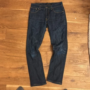 Raw Nudie Jeans - TVÄR feta mörkblå jeans med skit snygg tvätt från Nudie Jeans med klassisk femficksdesign och kontrastsömmar. Slim model och coola broderade detaljer på bakfickorna. Passar dig som gillar stilrena och tidlösa jeans med schysst passform. Model thinn Finn 