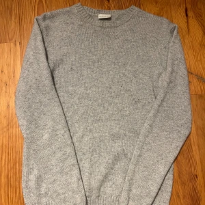 Grå stickad tröja från John Henric - Grå stickad tröja från John Henric i storlek S. Tröjan har rund halsringning och är tillverkad i en lyxig blandning av 90% ull och 10% kashmir. Perfekt för lager-på-lager och chill höst- och vinterstil. Använd men inga tecken på slitage