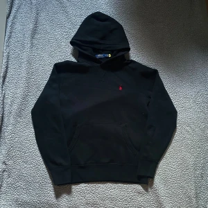 Svart hoodie från Polo Ralph Lauren - Svart hoodie från Polo Ralph Lauren med klassisk röd logga broderad på bröstet👕 mycket bra skick, inga hål✅ skickar snabbt efter att du har beställt.