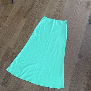 Mintgrön långkjol från ASOS - Säljer en snygg mintgrön långkjol från ASOS i slät och lätt glansig polyester. Kjolen har en enkel A-linjeform och stängs med en diskret dragkedja i sidan.