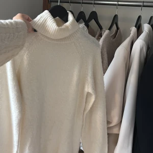 Vit stickad poloklänning - Supermysig vit stickad klänning med polokrage och långa ärmar. Den är kort i modellen och har en loose fit som ger en chill och trendig vibe. Perfekt att styla med boots och accessoarer för en snygg look.