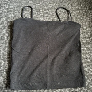 Svart linne från Gina Tricot storlek XS - Svart linne från Gina Tricot i storlek XS. Toppen har smala axelband med dubbel tyg. Inga defekter med väl använd.