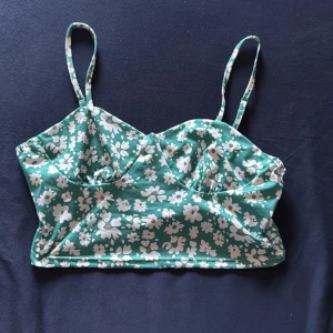 Grön blommig linnetopp med smala axelband - Supersöt grön linnetopp med vita blommor och smala axelband. Toppen är aldrig använd förutom när jag provat den. storlek Medium