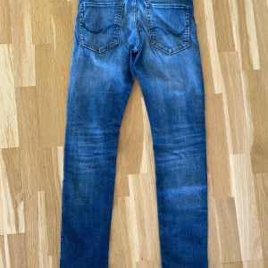 Slim jeans från Jack & Jones modell ”Glenn” - Snygga blå jeans från Jack & Jones i modellen Slim Glenn. Jeansen har en slim passform, klassisk femficksdesign och snygga slitningar på benen. 