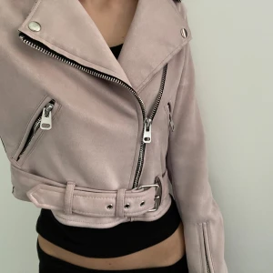 Ljusrosa mockajacka från Bershka XS - Säljer en ljusrosa mockajacka från Bershka. Jackan är croppad med bälte i midjan, silvriga dragkedjor och knappar samt långa ärmar. Skriv gärna om du undrar något 😊