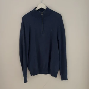 Blå stickad half zip från Polo Ralph Lauren - Mörkblå stickad tröja från Polo Ralph Lauren med half zip-dragkedja och hög krage. Klassisk och stilren modell med långa ärmar och ribbade muddar. Perfekt för lager-på-lager och snygg till jeans eller chinos. Nypris: 1800kr. Pris kan diskuteras!