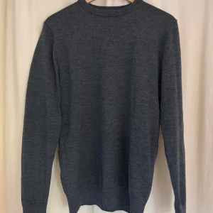Mörkgrå merinoulltröja John Henric - Säljer en stilren mörkgrå tröja från John Henric i 100% merinoull. Klassisk rund halsringning och långärmad modell, perfekt för lager-på-lager. Enkel och clean look som funkar till allt. Supermjuk och skön mot huden.