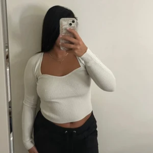 Vit ribbad croppad tröja med öppen rygg - Säljer en vit, ribbad och croppad långärmad tröja med snygg öppen rygg. Tröjan har en figurnära passform och är tillverkad i ett stretchigt stickat material. 