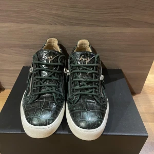 Giuseppe Zanotti -  Giuseppe Zanotti med grönt krokodilpräglat skinn, gröna snören och vita sulor. Skorna har dragkedjor på sidorna och den ikoniska signaturen i guld på plösen. Perfekta för dig som vill sticka ut med lyxig streetstyle.