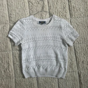 Vit stickad topp - Superfin vit stickad topp från OVS. Tröjan har ett snyggt hålmönster och ribbade muddar vid ärmslut och nederkant. Perfekt till vår och sommar för en fräsch och stilren look.