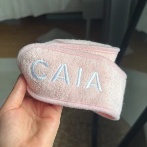 Rosa frotté diadem från CAIA - Säljer ett mjukt och fluffigt rosa diadem från CAIA i frotté med broderad logga framtill. Perfekt när du vill hålla håret borta vid sminkning eller hudvård. Sitter bekvämt och är lätt att justera.