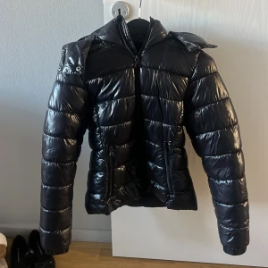 Svart Nikki jacka  - Snygg svart jacka från 157 modellen Nikki. Jackan har huva, långa ärmar och dragkedja framtill samt två dragkedjefickor. Perfekt för kalla dagar när du vill hålla stilen och ändå vara varm. Storlek xxs och sann i storlek. Köpt för 350kr förra året, använd ca 5 gånger men inga defekter alls. 