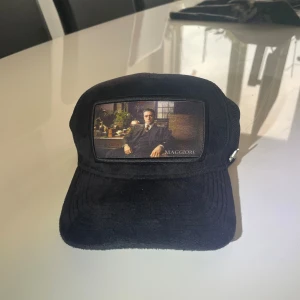 Svart Maggiore keps - Svart keps från Maggiore med konstnärligt motiv framtill. Framsidan är i mjuk manchester och baksidan har mesh för extra ventilation. Justerbar passform med snapback och liten metallogo på sidan. Perfekt för dig som vill sticka ut med en unik accessoar. Nypris på kepsen är cirka 600 kr