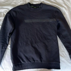 Svart sweatshirt från BOSS - Snygg svart sweatshirt från BOSS med diskret logga på bröstet. Tröjan har rund halsringning, ribbade muddar och är tillverkad i mjuk bomull. Perfekt för en clean och stilren look.