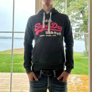 Superdry Hoodie - Svart Superdry hoodie i mycket bra skick | Storlek: XS | Jag är 182cm och väger 65kg📏| Vid frågor eller diskussion om pris är det bara att skriva ✍🏼 | Frakt inom 48h📦