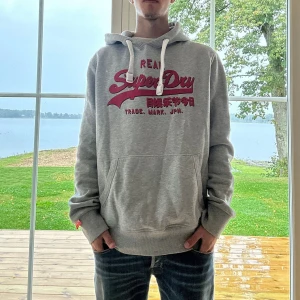 Superdry Hoodie - Grå Superdry hoodie i mycket bra skick | Storlek: L | Jag är 182cm och väger 65kg📏| Vid frågor eller diskussion om pris är det bara att skriva ✍🏼 | Frakt inom 48h📦