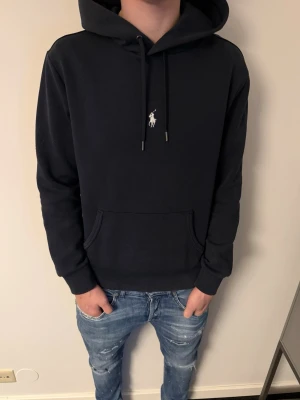 Ralph Lauren hoodie - Riktigt snygg Ralph Lauren hoodie i mörkblå färg. Tröjan är väldigt sparsamt använd och är i riktigt bra skick. Skriv för fler frågor eller funderingar!