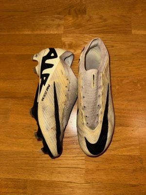 Nike Mercurial Zoom Vapor Elite fotbollsskor stl 41 - Säljer ett par Nike Mercurial Vapor Elite Zoom fotbollsskor i ljusbeige med svarta detaljer och stor Nike-logga. Perfekta för dig som vill ha snabbhet och stil på fotbollsplanen. De är använda inga skador. Inga snören. Storlek 41. Priset är förhandlingsbart. 