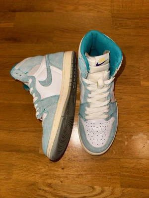Nike Air Jordan 1 Turbo Green High OG stl 41 - Säljer ett par Nike Air Jordan 1 High OG Turbo Green med vit läderbas och turkosblå mockadetaljer. Skorna har klassisk snörning, perforerad tå och ikoniska Air Jordan-loggan på sidan. Insidan är fodrad i turkos textil och sulan är i offwhite. Perfekta för dig som vill sticka ut. Storlek 41. Priset är förhandlingsbart 