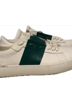 Valentino Garavani vita sneakers - Snygga vita sneakers från Valentino Garavani med bred grön rem över ovansidan och ikoniska nitar på hälen. Skorna har snörning och platt sula, tillverkade i skinn för en lyxig känsla. Perfekt för dig som gillar stilrena och exklusiva sneakers. Box ingår 