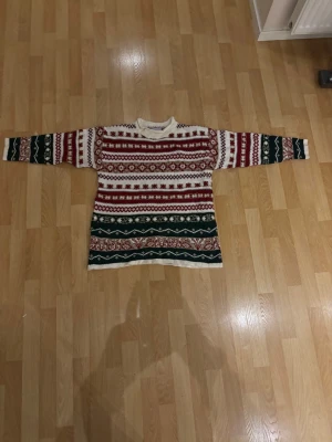 Mönstrad stickad tröja från Katies - Säljer en mysig stickad tröja från Katies med klassiskt mönster i vinrött, grönt och vitt. Tröjan har långärmad passform, rund hals och är perfekt för kalla dagar. Den har en loose fit och är tillverkad i mjukt stickat material. Storlek M ( uk storlek 12 )