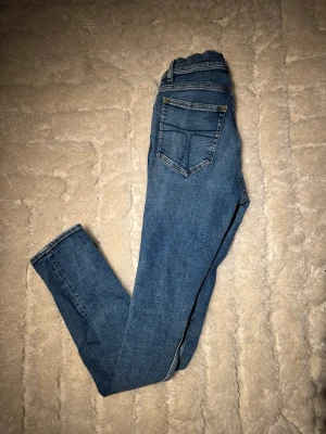 Tiger of Sweden blå jeans evolve 29/32 - Blå jeans från Tiger of Sweden i modellen Evolve. Klassisk femficksdesign med snygga kontrastsömmar och läderpatch bak i midjan. Jeansen har rak passform och är tillverkade i slitstarkt bomullsmaterial. Perfekt för dig som gillar stilrena och tidlösa jeans.