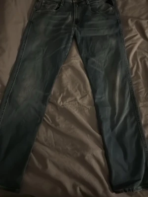 Replay Hyperflex blå jeans - Säljer ett par Replay Hyperflex jeans i klassisk blå tvätt med snygga slitningar och kontrastsömmar. Modellen har raka ben, fem fickor och brunt Replay-märke bak i midjan. snygg passform.