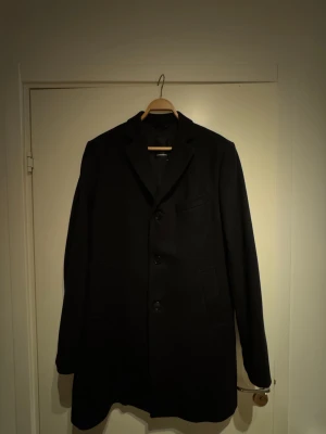 J.Lindberg Wolger Compact Melton rock - Stilren svart rock från J.Lindeberg i klassiska modellen ”Wolger Compact Melton”. Perfekt för dig som vill ha en tidlös och clean look. Storlek 50 motsvarar Medium.