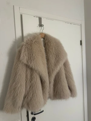 Beige fluffig pälsjacka - Säljer en superfluffig och snygg gammalrosa/beige pälsjacka med bred krage och lång ärm. Den är iprincip oandvänt då jag aldrig burit den utomhus utan bara testat hemma!💕 Storlek m