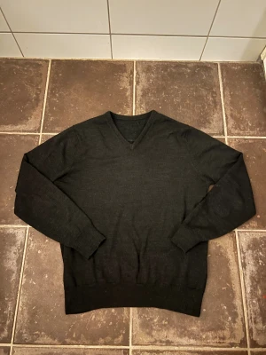 Callaway tröja - Svart stickad tröja från Callaway i storlek S med v-ringad hals och långa ärmar. Diskret logga i vitt på ryggen. Mjuk och skön känsla, perfekt för dig som gillar stilrena och klassiska plagg. Passar dig som vill ha en enkel men snygg look.