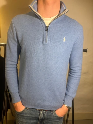  Polo Ralph Lauren - Snygg ljusblå stickad tröja från Polo Ralph Lauren med half zip och hög krage. Tröjan har lång ärm och klassisk broderad logga på bröstet. Perfekt för dig som gillar stilrena och bekväma plagg. Storlek S, nytt skick, ny pris 2000kr, mitt pris 349kr ✅. Hör av dig vid funderingar 📩