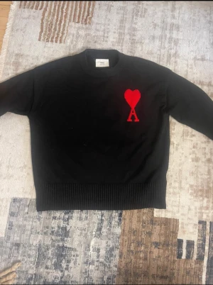 Ami paris tröja - Svart stickad tröja från Ami med rund hals och ribbade muddar. På bröstet finns ett rött hjärta med bokstaven A, som är typiskt för märket. Storlek S passform slim fit. Skriv vid eventuella frågor. Pris kan diskuteras.