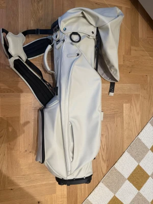 LINKSLEGEND Members Bag Titleist - 4-delad topp med avdelare i full längd Integrerat handtag på ovansidan för bättre funktionalitet och tillgång Velourfodrad peggficka och dold dryckesficka med magnetförslutning Vattenavvisande syntetmaterial av hög kvalitet och quiltade detaljer Dubbel bärsele i premiumkvalite  Inköpt i Juli och i väldigt bra skick. Ny pris 4799:-