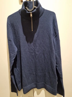 Marinblå polotröja Jack & Jones - Snygg marinblå polotröja från Jack & Jones med half zip-dragkedja i halsen. Tröjan har lång ärm och är stickad i mjukt material som känns skönt mot huden. Perfekt för dig som gillar stilren och enkel design med en modern touch.