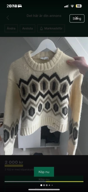 Stickad tröja från Ganni stl XS - Säljer en stickad tröja från Ganni i storlek XS. Tröjan är beige med svart och grått grafiskt mönster, har ribbad rund hals och långa ärmar. Modellen är lite croppad och har en chunky, cozy vibe som är perfekt för kyliga dagar.