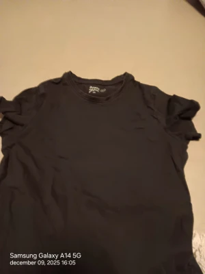 Svart basic t-shirt från Basic - En enkel svart t-shirt från Basici storlek xs. Modellen har rund hals och korta ärmar, perfekt för en clean och chill stil. Materialet är mjuk bomull som känns skönt mot huden. Passar dig som gillar klassiska och stilrena plagg.