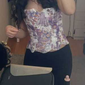 Lila och vit korsett från Plt - Trendig korsett i lila och vitt med unikt hålmönster och vågig nederkant. Toppen har en figurnära passform och är perfekt för att skapa en cool och edgy look. 