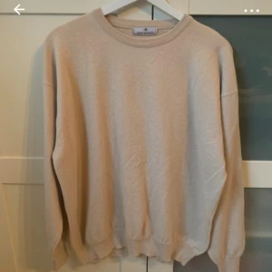 Beige stickad tröja från Don Miguel - En stilren beige stickad tröja från Don Miguel med rund halsringning och långa ärmar. Tröjan har en klassisk passform och ribbade muddar vid ärmslut och nederkant. Perfekt för lager-på-lager under kyliga dagar. Ull och bomull. 