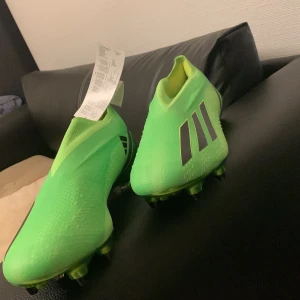 Gröna adidas fotbollsskor utan snörning - Säljer ett par grymt snygga fotbollsskor från adidas i neon-grönt med svarta ränder på sidorna.  Sulan är grön och har fasta dobbar för bästa grepp på planen. Priset kan diskuteras.