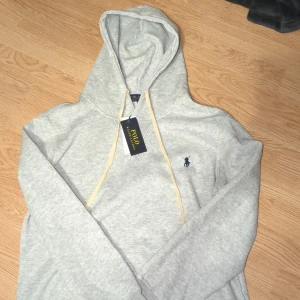 Grå hoodie från Polo Ralph Lauren - Det Ralph Lauren hoodie med väldigt bra skick. Endast använd 1 gång. Mjuk och skön och perfekt till alla outfits. Kom dm om minsta frågan. Priset är ej hugget i sten.