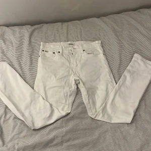 Vita jeans från Polo Ralph Lauren - Snygga vita jeans från Polo Ralph Lauren med klassisk femficksdesign och bruna nitar. De har rak passform och är tillverkade i mjukt bomullsmaterial. Märkespatch i läder baktill och diskreta Polo-loggor på fickorna ger en clean och stilren look.