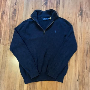Navy quarter zip tröja Polo Ralph Lauren - Äkta Navy quarter zip från Ralph lauren 🐎        - längd (65cm), bredd (47cm), ärm (60cm)         8/10 skick, finns ett litet hål på framsidan men annars inga defekter, qr kod finns                  Hör av er 🫡
