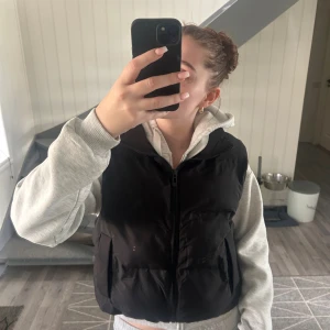 Svart väst från Zara, strl M - Säljer en svart dunväst från Zara i storlek M. Västen har en hög krage, två fickor framtill och stängs med dragkedja. Materialet är polyester, vilket gör den lätt och bekväm. Bra skick! 